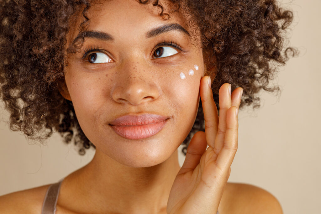 Charming young lady looking at side with dots of face cream on her cheek
